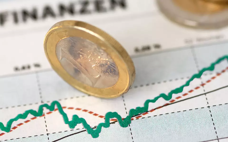 1-Euro-Münze steht senkrecht auf Zettel mit Diagramm
