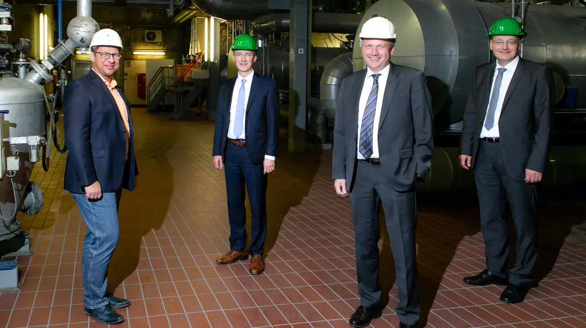 Daniel Benedict (MVK-Prokurist), Frank Meier (SWK-Vorstandsvorsitzender), Dr. Frank Ehlers (MVK Geschäftsführer) und Dr. Jörg Teupen (SWK-Vorstand) stehen im Kesselhaus der MVK vor den Fernwärmeleitungen