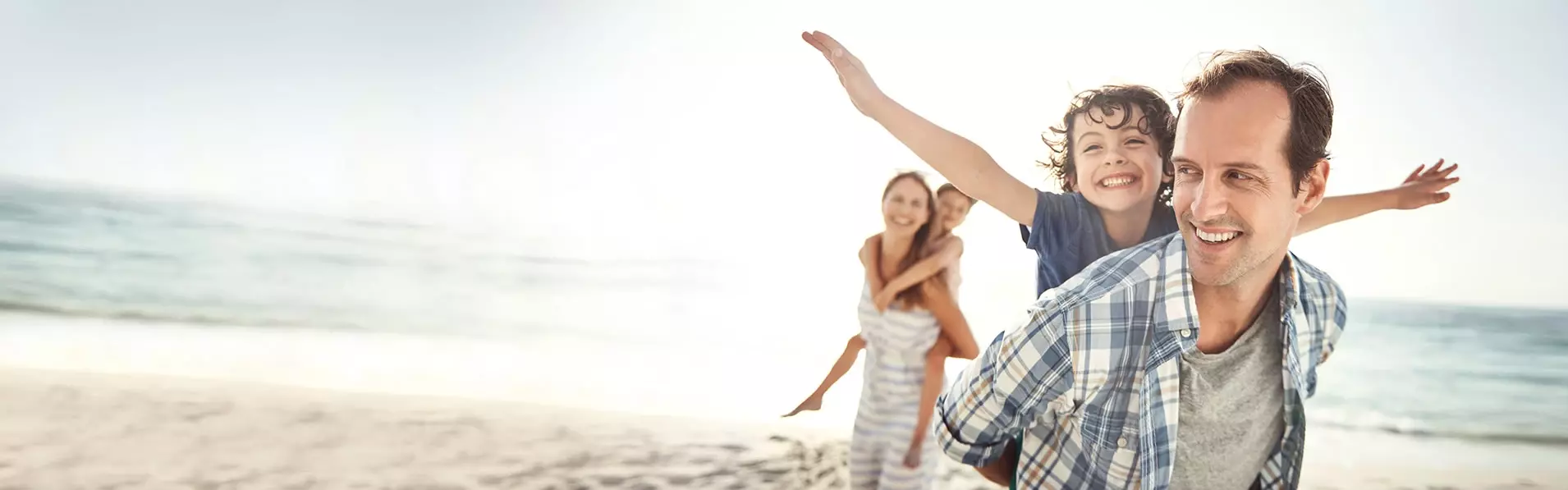 Familie lachend und spielend am Strand