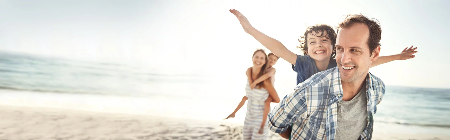 Familie lachend und spielend am Strand