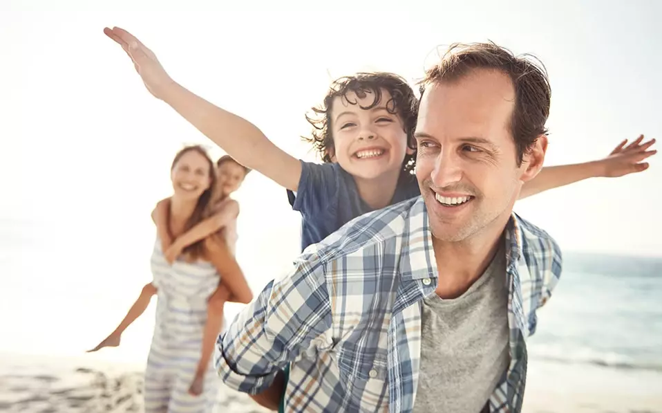 Familie lachend und spielend am Strand