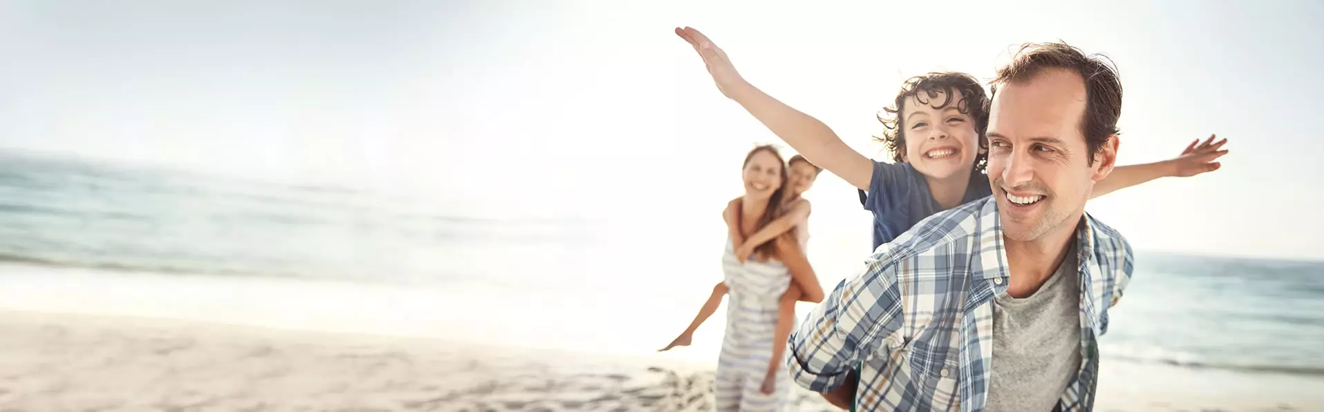 Familie lachend und spielend am Strand
