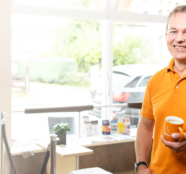 Lächelnder Mann von der Kaffeeküste Laboe mit Kaffeetasse in der Hand