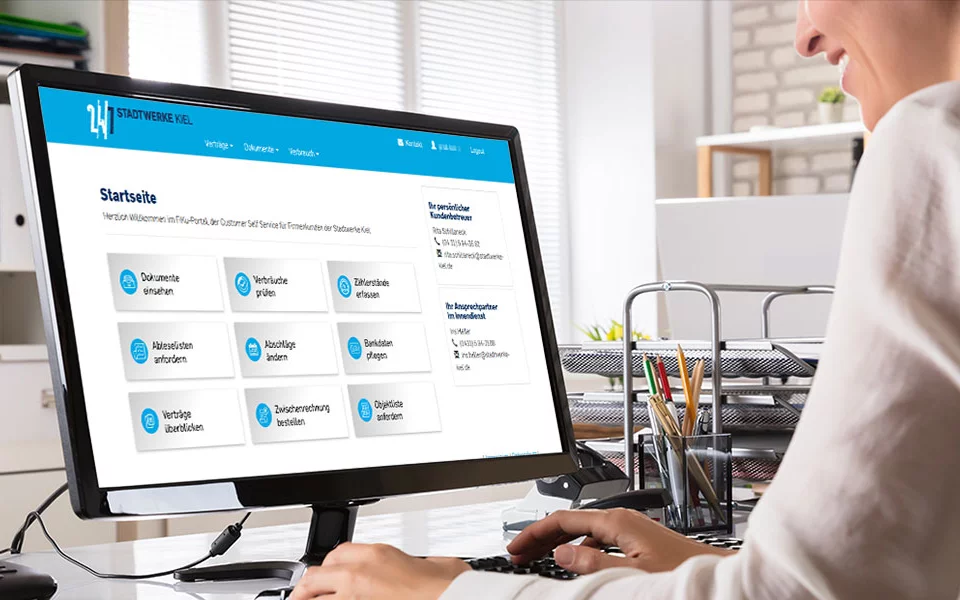 Frau im Büro blickt auf Monitor mit geöffneter Startseite FiKu-Portal