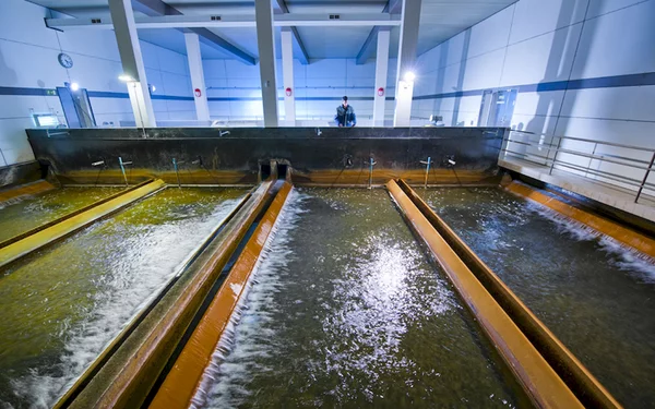 Filterbecken mit Quarzkies im Wasserwerk, ein Mitarbeiter im Hintergrund.