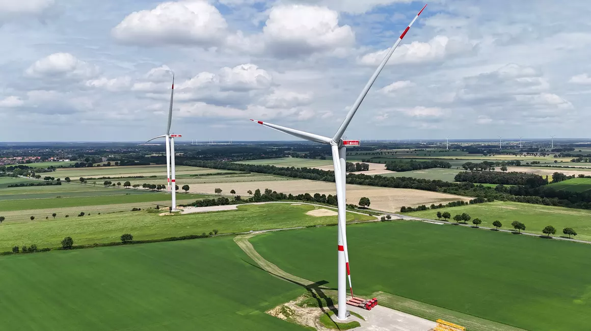 Zwei Windkraftanlagen auf grüner Wiese.