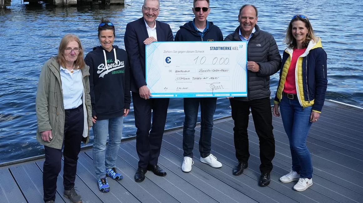 An der Benefiz-Ruderregatta-Rennstrecke übergab Dr. Jörg Teupen (3.v.li.) den Spendenscheck an Dr. Roland Ventzke (2.v.re.), Karin Peter (li.), Rudergesellschaft Germania Kiel, Astrid Schulz (2.v.li.), Leitung Sportprogramm Krebspatienten im SKK, Andreas Harm (3.v.re.), Erster Kieler Ruder-Club, und Julia Kuntze, Leiterin Patienten-Krebsrudergruppe und Rudergesellschaft Germania Kiel.