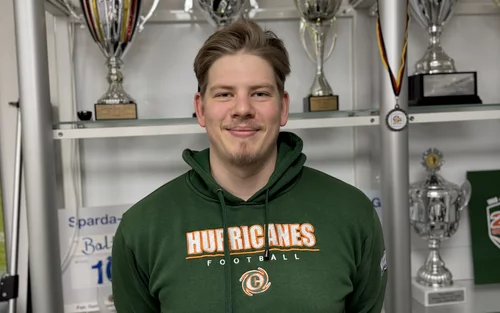 Tristan Thormählen, mit einem Baltic Hurricanes Pullover der in die Kamera lächelt. Ein junger Mann mit blonden Haaren und einem leichten Kinnbart