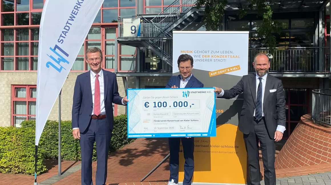 Vor dem Casino der Stadtwerke Kiel, in dem das Benefizkonzert „Phil Energie“ am 29. September stattfindet, überreichte Frank Meier (li.) den Spendenscheck an Benjamin Reiners (mi.) und Hendrik Murmann.